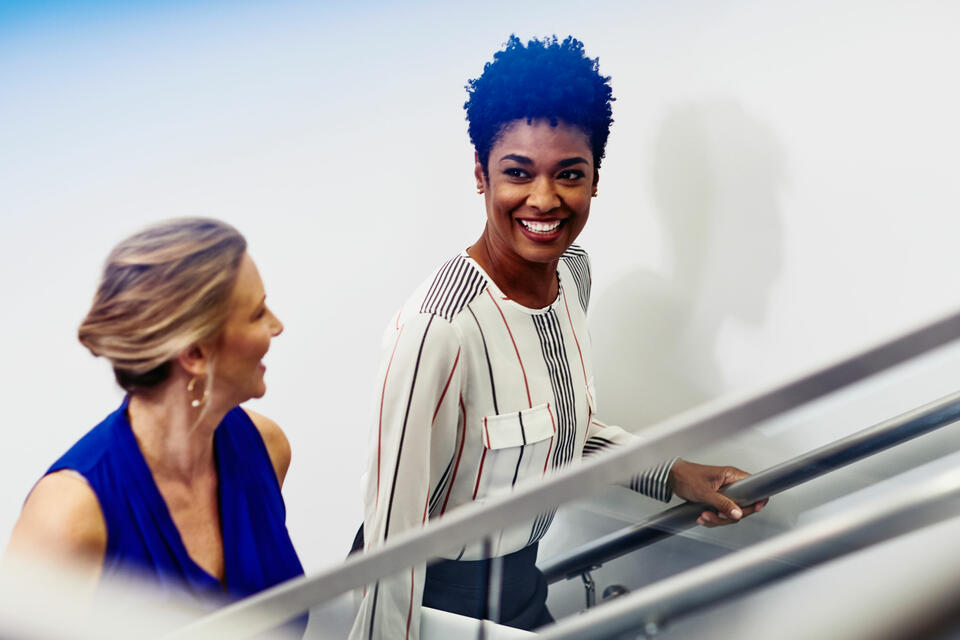 an image of two women talking while climbing a flight of stairs