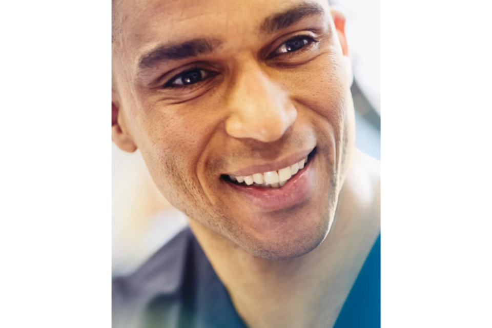 an image of a man wearing scrubs while smiling