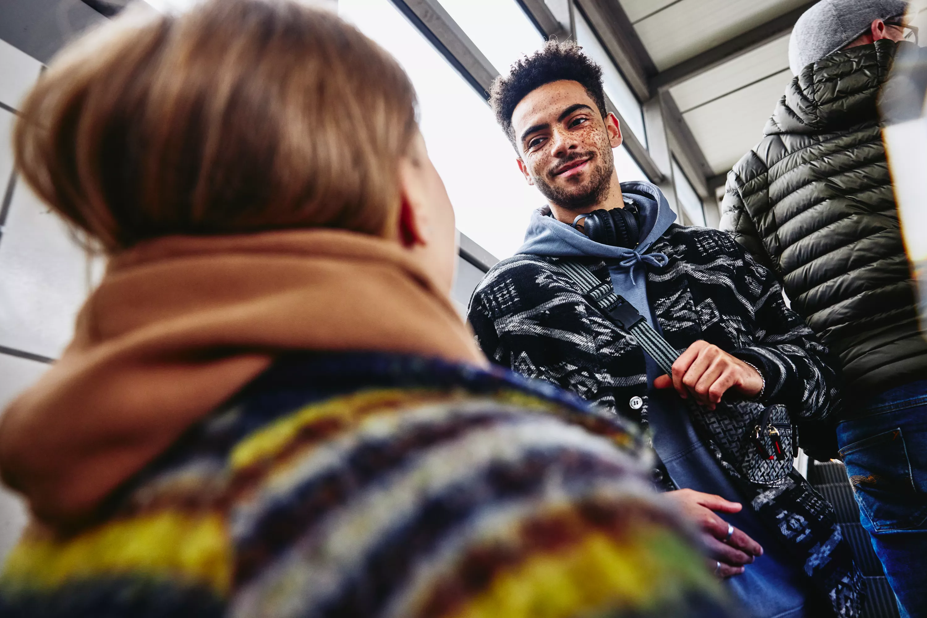 smiling male standing backwards on escalator looking at a female at a train station