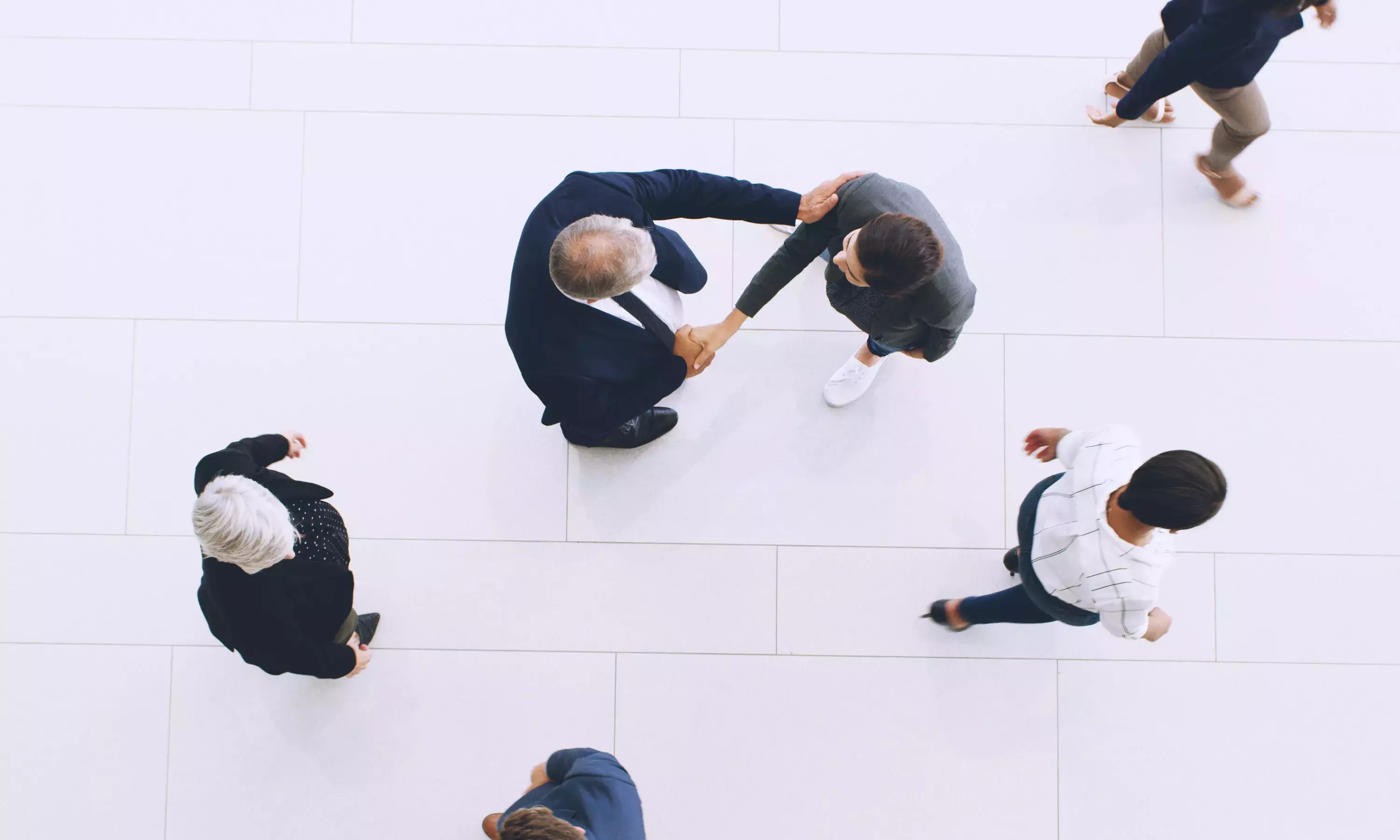 Aerial view of two people shaking hands while people walk by.