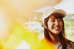Smiling woman wearing a white cap looking at the far right