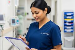 a nurse working in a hospital writing on a piece of paper attached to a clipboard