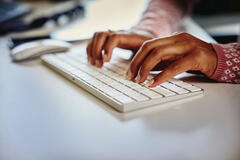 image of two hands typing on a keyboard with a mouse next to the keyboard