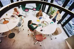 Bird view of people sitting and standing at a round table and having a meeting