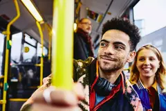 Womale and boy smiling, sitting in a bus.
