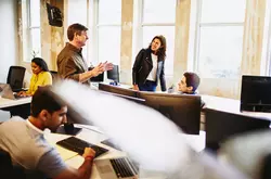 group of smiling colleagues in an office having a conversation