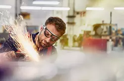 male wearing safety glasses, grinding metal

