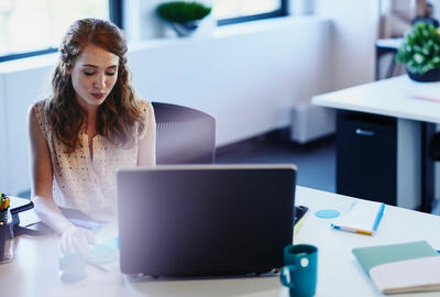 woman sitting at a desk behind a laptop