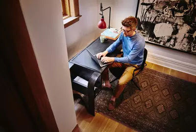 an image of a birds eye view of male sitting at a desk working on his laptop