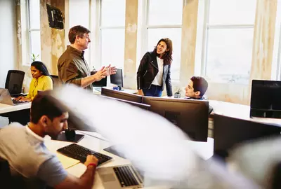 group of smiling colleagues in an office having a conversation