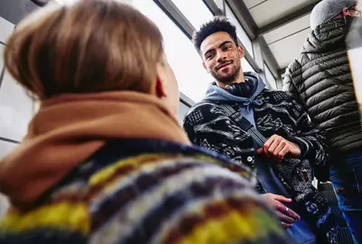 smiling male standing backwards on escalator looking at a female at a train station
