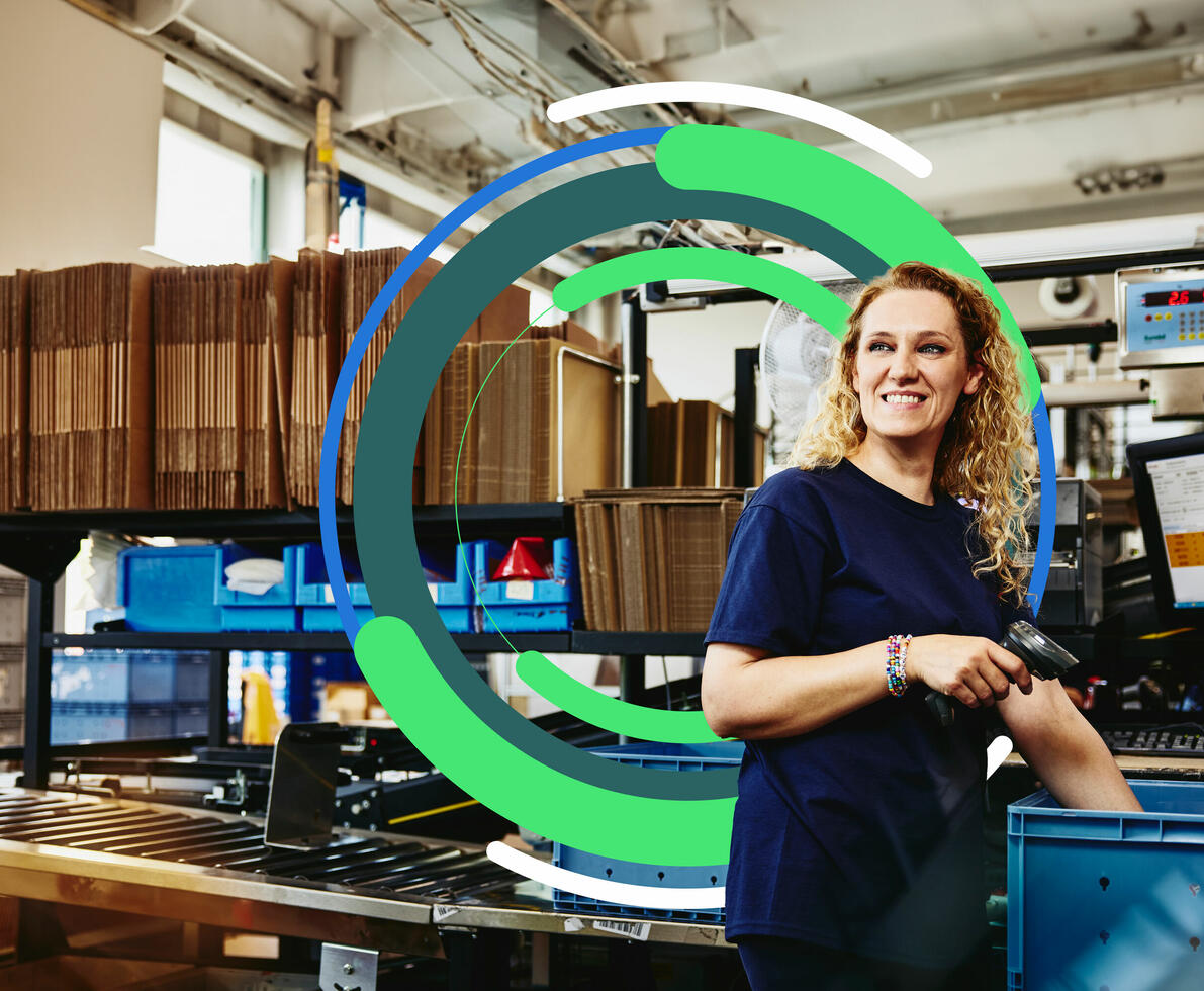 an image of a woman working standing next to conveyer belt holding a scanner while smiling brightly