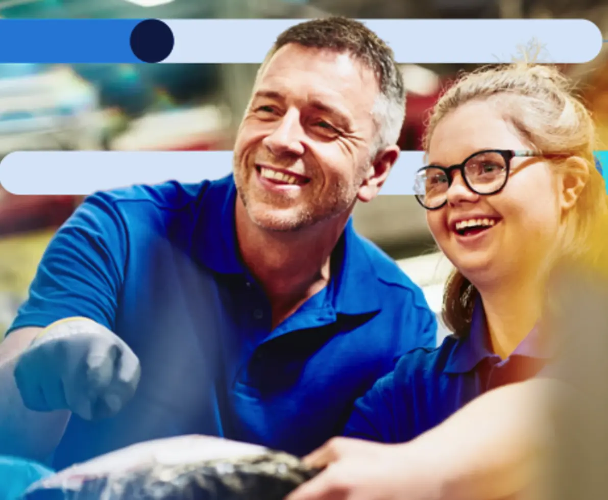 man with gloves and blue shirt working with a young girl with black rimmed glasses 