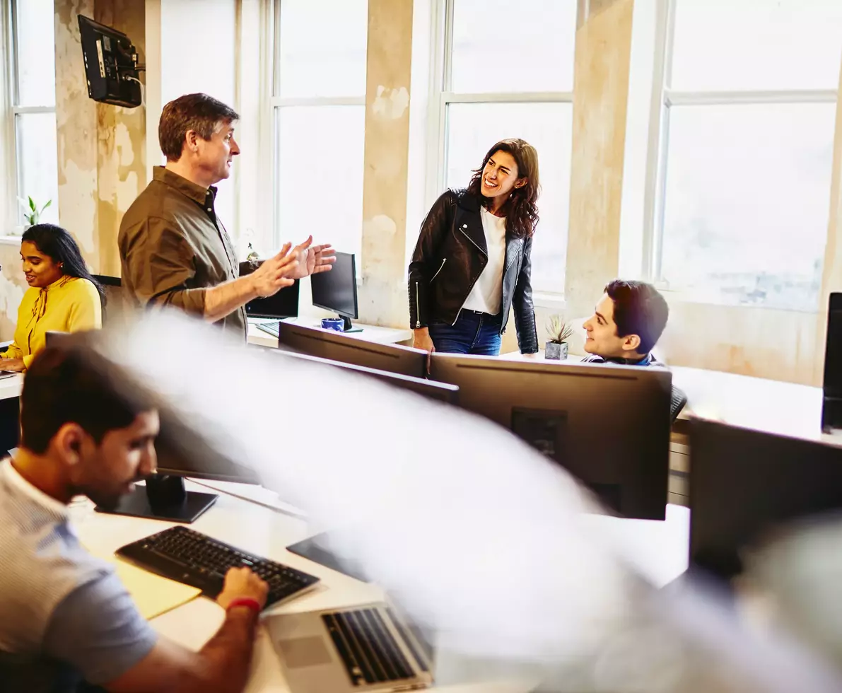 group of smiling colleagues in an office having a conversation