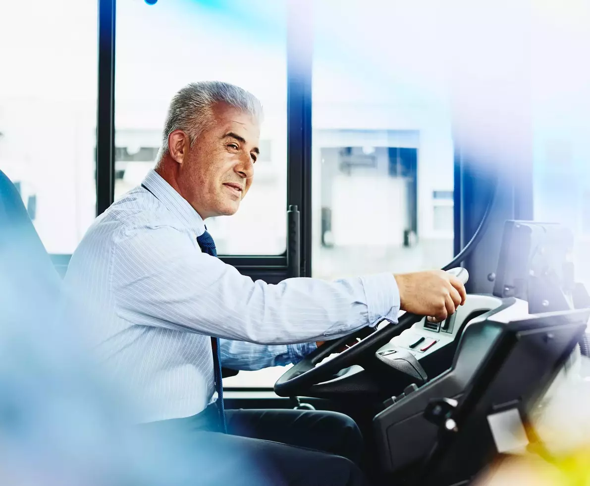 Male bus driver behind the steering wheel on the bus
