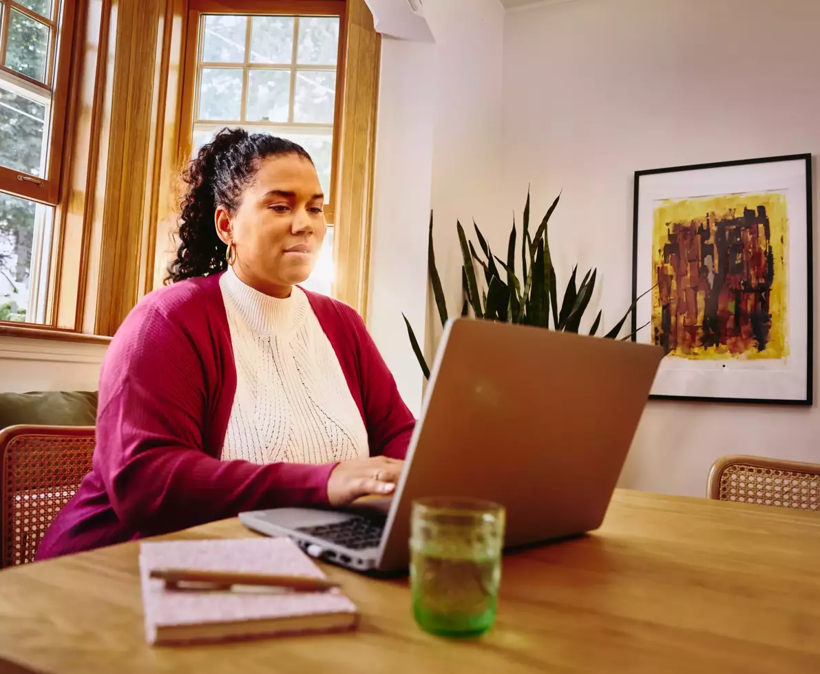 Female working on laptop on a table at home
