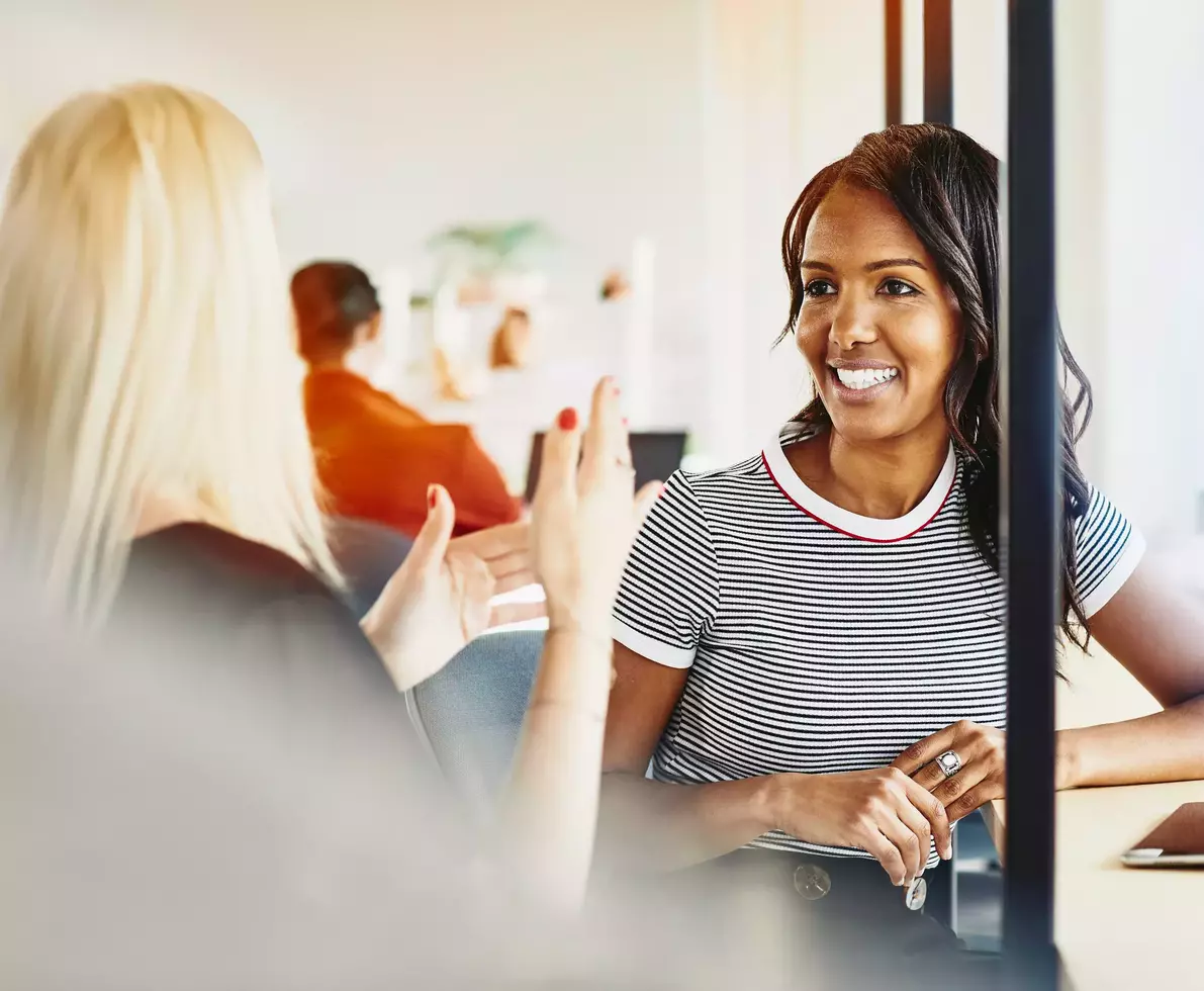 Two female having a conversation. Smiling.

