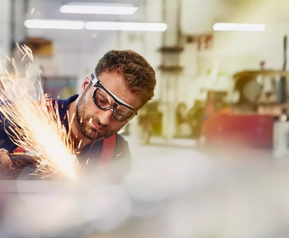 male wearing safety glasses, grinding metal
