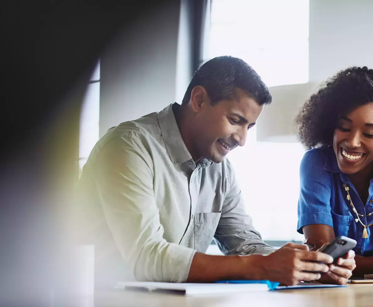 Smiling male and female looking down at phone