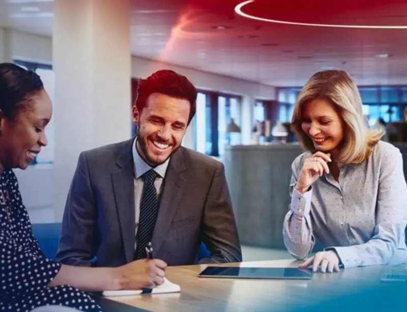 two women and a man in the middle talking in an office space