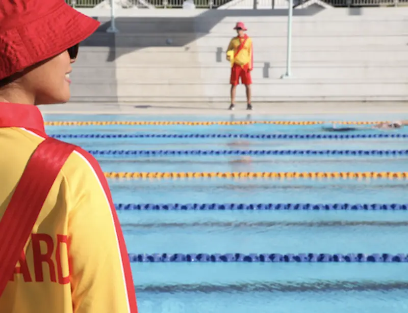 two female lifeguards standing on the side of the pool