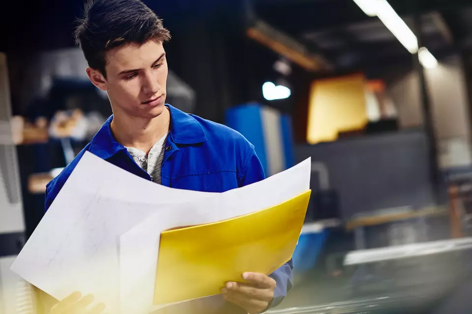 male looking down at papers in a production site/factory